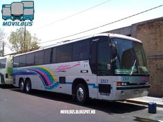 two buses parked next to each other in front of a brick building on the street