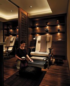 a woman sitting on a chair in a room filled with chairs and other furniture,