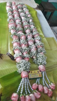 pink flowers are arranged in rows on a banana leaf table with other items around it