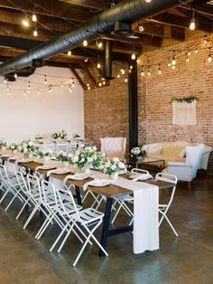 a long table with white flowers and greenery is set up for a wedding reception