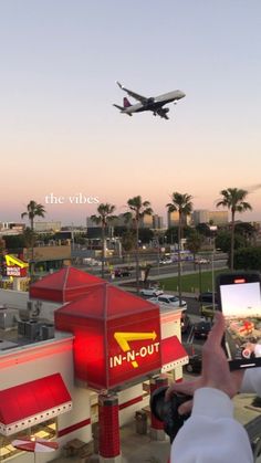 an airplane is flying in the sky over a fast food restaurant with cars and trucks