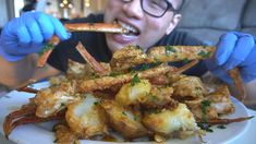 a man in blue gloves is eating some food on a white plate with shrimp sticks