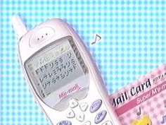 an old cell phone sitting on top of a pink checkered tablecloth with the words mail card in front of it