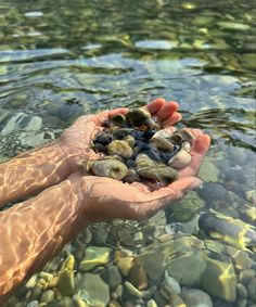 a person holding rocks in their hands over the water