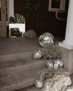 some silver balls are sitting on the steps outside an apartment building with moss growing out of them