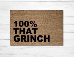 a door mat with the words 100 % that grin written in black on it, against a white wooden background