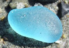 a blue rock sitting on top of a sandy beach