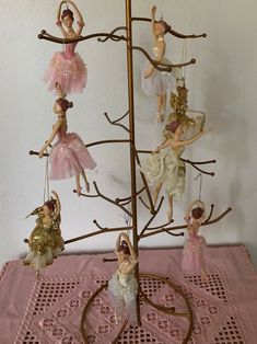 a group of figurines hanging from a tree on top of a doily covered table