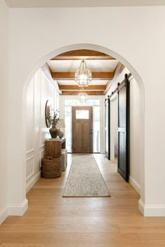 an archway leads into a foyer with wood floors and white walls, along with a large rug on the floor