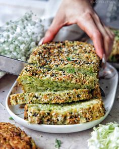 someone is cutting up some bread on a plate with other food items in the background