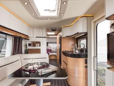 the interior of a motor home with wood flooring and white walls, along with a dining area