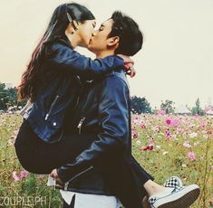 a man and woman kissing in a field of flowers