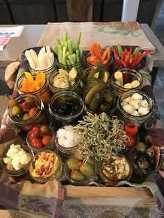 a table topped with lots of jars filled with different types of vegetables and dips