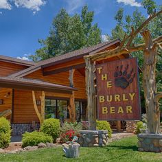 the burly bear sign is in front of a wooden building with trees and bushes around it