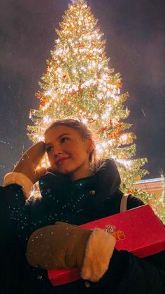 a woman standing in front of a christmas tree