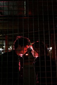 a man and woman standing next to each other in front of a caged area