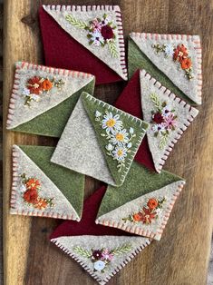 several pieces of fabric with flowers on them sitting on top of a wooden table next to each other