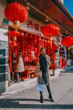 a woman standing in front of a store with red lanterns