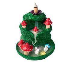 a green cake with red mushrooms and other decorations on it's top, sitting in front of a white background