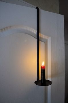 a candle is lit in the corner of a door handle on a white painted wall