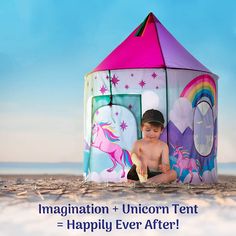 a little boy sitting in front of a tent on the beach