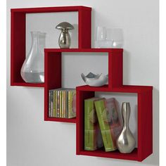 three red shelves with books, vases and other items in them on the wall