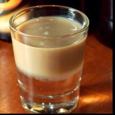 a glass filled with liquid sitting on top of a wooden table