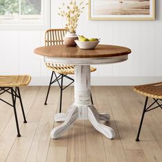 a dining table with two chairs and a bowl of fruit on top of the table