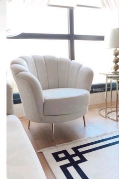 a white chair sitting on top of a hard wood floor next to a large window