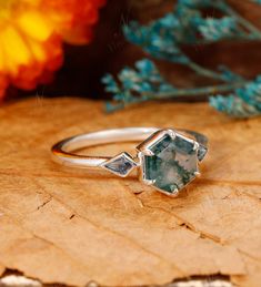 a close up of a ring on top of a piece of wood with flowers in the background