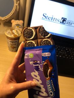 a person holding up a bag of oreo cookies in front of a laptop computer