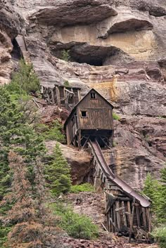 an old wooden structure on the side of a mountain