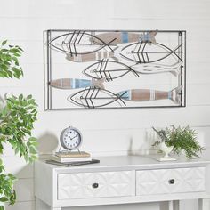 a white table topped with a clock next to a potted plant and a mirror