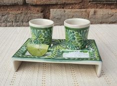 two cups and a lime on a tray