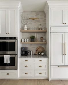 a kitchen with white cabinets and open shelving above the stove is pictured in this image