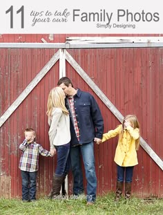 a man and woman holding hands while standing next to two small children in front of a red barn