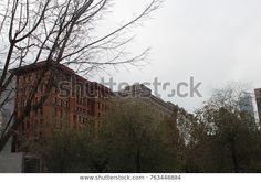 an old brick building in the city with bare trees and no leaves on it's branches