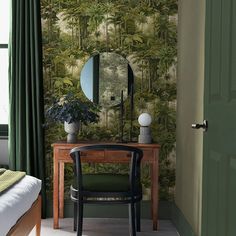 a bedroom with a mirror, desk and chair in front of a green wallpaper