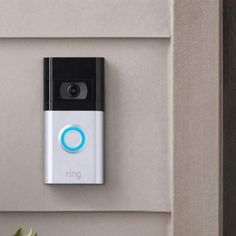 a ring video camera mounted to the side of a wall next to a potted plant