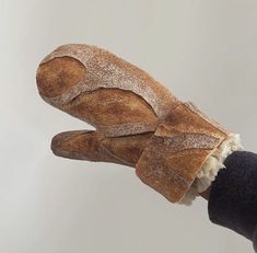 a person holding a loaf of bread in their right hand and wearing a pair of black gloves