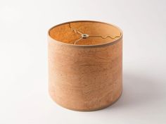 a small wooden container with a string attached to it's side, sitting on a white surface