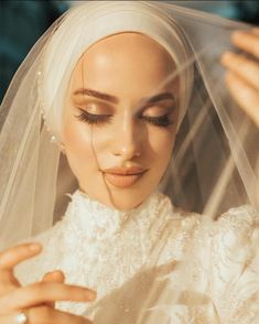 a woman wearing a veil and holding her hands up to her face