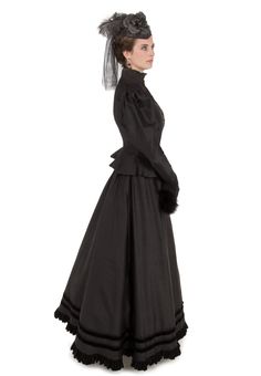 The traditional late-Victorian silhouette is accomplished beautifully with a closely-fitted bodice featuring a high neckline with a stand-up collar made of shirred black silk chiffon and trimmed in lace, with many small buttons closing the front. A gently ruffled peplum skims over the hips. Large poufed sleeves taper to lace-trimmed narrow cuffs, which have an additional black silk chiffon deep ruffle at the wrist. The hem of the matching skirt is finished with a black velvet ruffle, just below Victorian Fitted Dress For Costume Party, Fitted Victorian Historical Dress, Fitted Victorian Dress Costume, Black Victorian Dress With Fitted Bodice, Victorian Dress With Ruffles And Fitted Bodice, Fitted Regency Victorian Dress For Costume Party, Black Fitted Victorian Dress For Costume Party, Classic Victorian Dress For Costume With Fitted Bodice, Classic Victorian Dress With Fitted Bodice For Costume