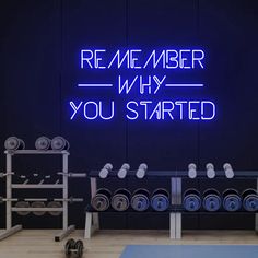 a neon sign that reads,'remember why you started'with dumbs in front of it