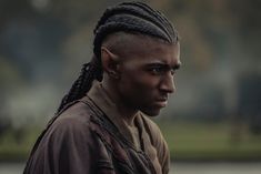 a man with dreadlocks standing in the park