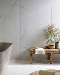 a bath tub sitting next to a wooden bench in front of a white tiled wall