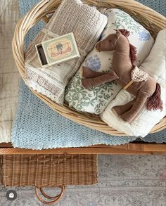 a wicker basket filled with blankets and stuffed animals on top of a wooden table