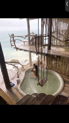 a person in a hot tub on the deck of a beach house next to the ocean