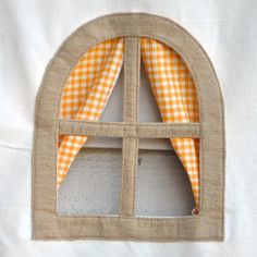 an open window with orange and white checkered fabric on the curtain is shown in front of a white background