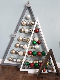 a christmas tree with ornaments on it and a wooden stand in front of the wall